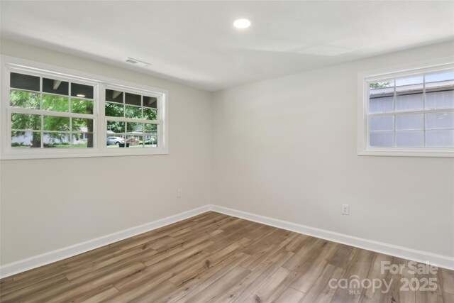 empty room with baseboards, wood finished floors, and recessed lighting