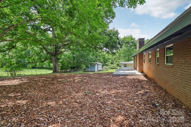 view of yard with an outbuilding, a storage shed, a patio area, and fence