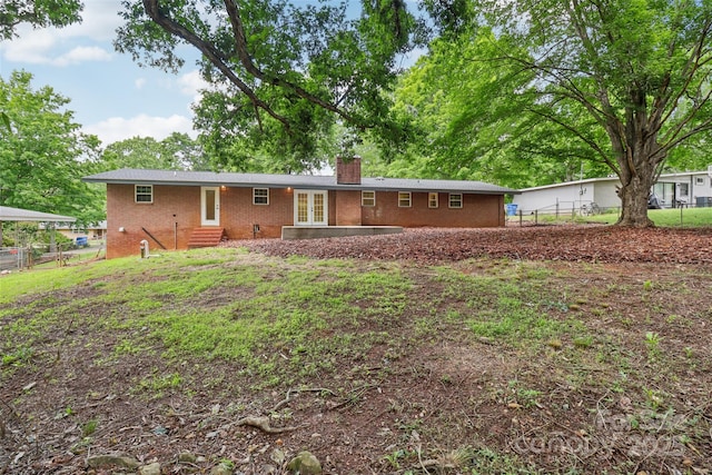 back of property featuring entry steps, french doors, brick siding, a chimney, and fence