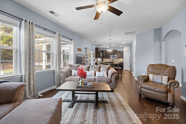 6119 Castlecove Rd, Charlotte, NC 28278 - living room featuring dark wood-style flooring, ceiling fan, arched walkways, and baseboards