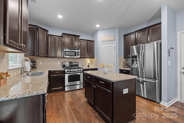 6119 Castlecove Rd, Charlotte, NC 28278 - kitchen featuring stainless steel appliances, a sink, dark brown cabinets, dark wood-style floors, and light stone counters