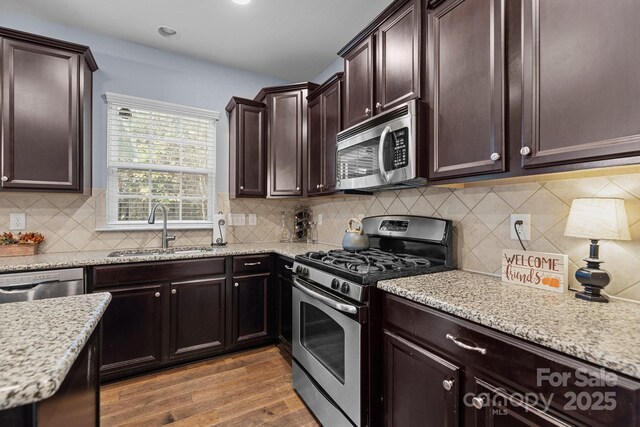 6119 Castlecove Rd, Charlotte, NC 28278 - kitchen with appliances with stainless steel finishes, a sink, wood finished floors, light stone countertops, and recessed lighting