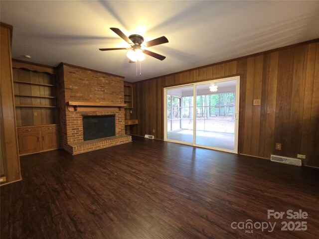 3316 Mckee Rd, Charlotte, NC 28270 - unfurnished living room featuring ceiling fan, a fireplace, wooden walls, and dark wood-type flooring