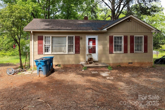 view of front of house featuring crawl space, a shingled roof, and a chimney