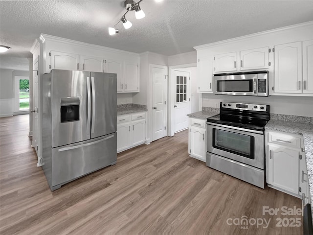 2532 Steeplechase Rd, Gastonia, NC 28056 - kitchen featuring appliances with stainless steel finishes, a textured ceiling, white cabinetry, light wood finished floors, and light stone countertops