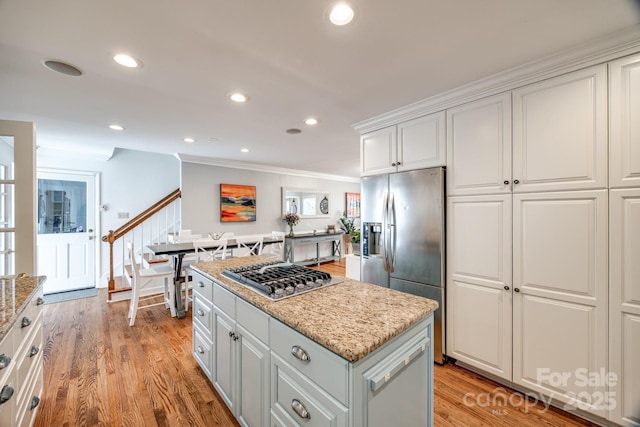 2702 Oxborough Dr, Matthews, NC 28105 - kitchen featuring stainless steel appliances, crown molding, a center island, white cabinetry, and light wood finished floors