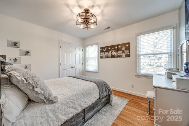 2702 Oxborough Dr, Matthews, NC 28105 - bedroom with light wood-style floors, baseboards, a chandelier, and a closet