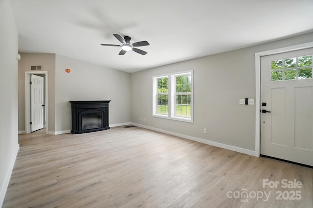 12382 Ritchie Rd, Midland, NC 28107 - unfurnished living room with healthy amount of natural light, light wood-type flooring, a ceiling fan, and a glass covered fireplace