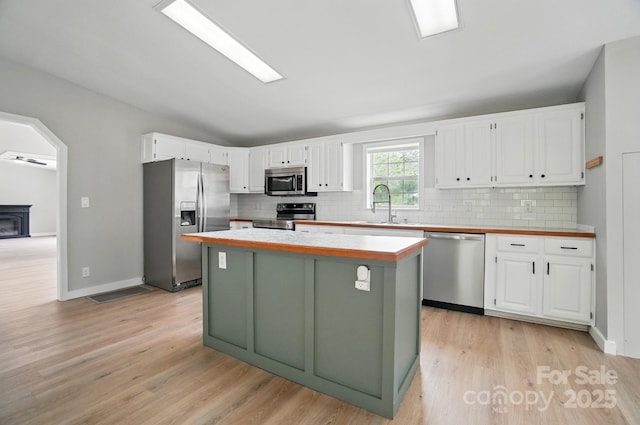 12382 Ritchie Rd, Midland, NC 28107 - kitchen featuring appliances with stainless steel finishes, a sink, white cabinets, decorative backsplash, and lofted ceiling