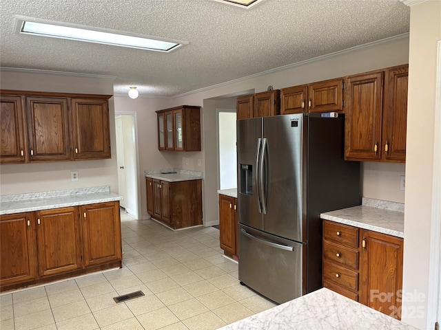 1896 Green Creek Dr E, Tryon, NC 28782 - kitchen featuring stainless steel refrigerator with ice dispenser, a textured ceiling, light countertops, crown molding, and brown cabinetry