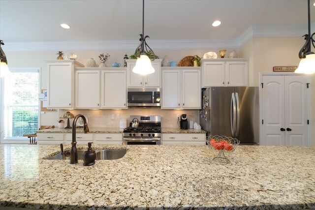 8818 Artesa Mill Ln, Charlotte, NC 28214 - kitchen featuring appliances with stainless steel finishes, a sink, white cabinetry, light stone counters, and hanging light fixtures