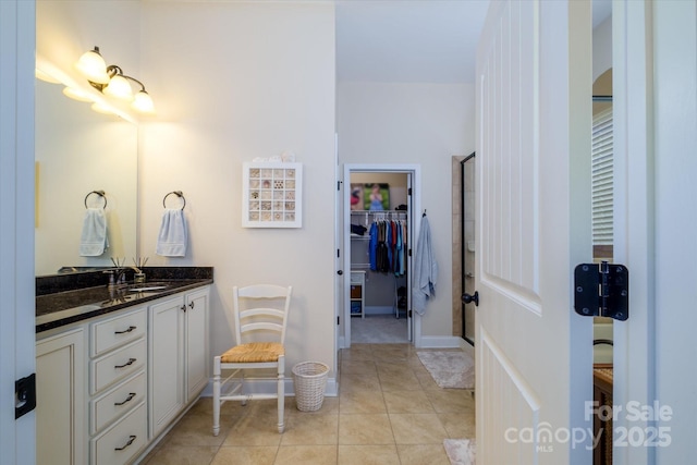 8818 Artesa Mill Ln, Charlotte, NC 28214 - bathroom with vanity, a walk in closet, tile patterned floors, a shower with shower door, and baseboards