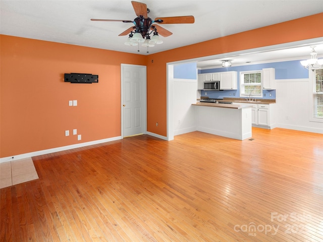 unfurnished living room featuring a sink, ceiling fan, and light wood-style flooring