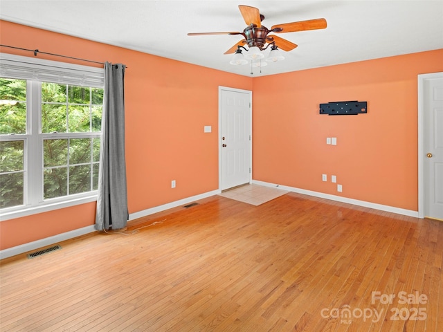 unfurnished room featuring baseboards, light wood-type flooring, and a ceiling fan