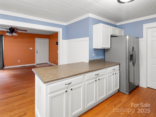 kitchen with a ceiling fan, a peninsula, white cabinetry, stainless steel refrigerator with ice dispenser, and crown molding