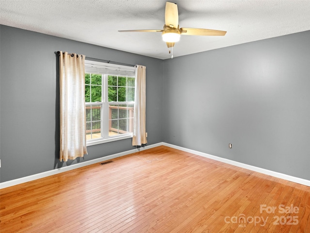 spare room with wood finished floors, ceiling fan, baseboards, and a textured ceiling