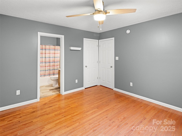 unfurnished bedroom featuring light wood-type flooring, baseboards, and ensuite bathroom