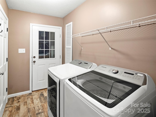 laundry room featuring independent washer and dryer, light wood-style flooring, and baseboards