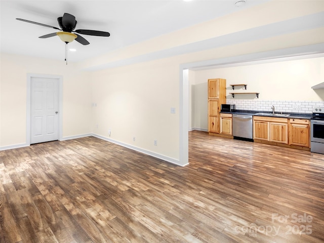 unfurnished living room featuring wood finished floors, baseboards, a sink, and ceiling fan