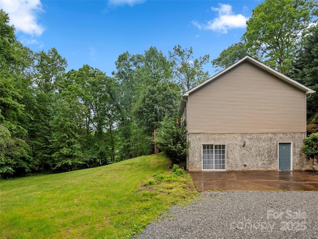 view of side of home featuring a lawn, a patio area, and stucco siding