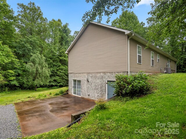 view of side of home featuring a yard, cooling unit, a patio area, and stucco siding