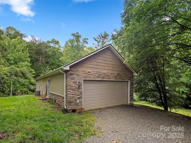 view of side of home featuring stone siding, central AC, a detached garage, and a lawn