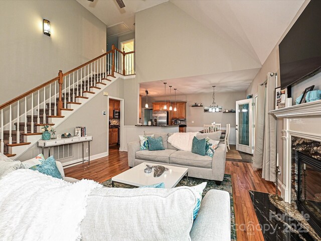 3409 Valdosta Ct, Monroe, NC 28110 - living room with stairs, wood finished floors, a towering ceiling, a fireplace, and a chandelier