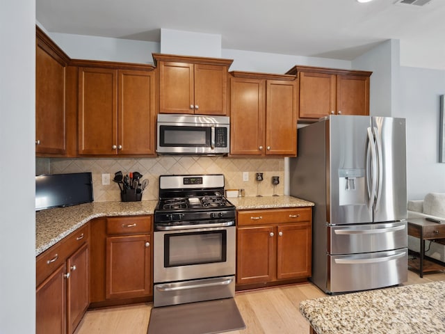 3306 Yarmouth Ln, Gastonia, NC 28056 - kitchen featuring appliances with stainless steel finishes, light wood finished floors, light stone counters, and brown cabinetry