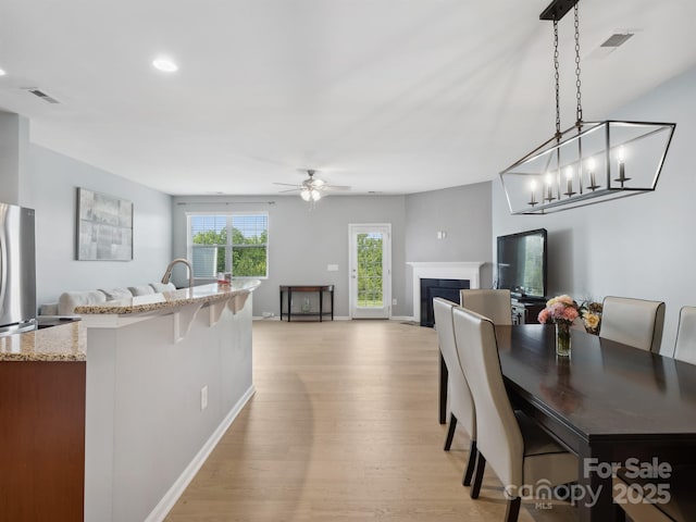 3306 Yarmouth Ln, Gastonia, NC 28056 - dining space featuring light wood-style flooring, a fireplace, and ceiling fan