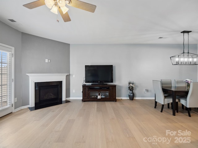 3306 Yarmouth Ln, Gastonia, NC 28056 - living area featuring light wood finished floors, ceiling fan, and a fireplace with flush hearth