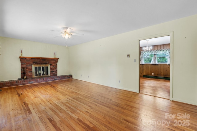 713 Crozet St NW, Valdese, NC 28690 - unfurnished living room featuring ceiling fan, light wood-type flooring, a baseboard radiator, and a brick fireplace