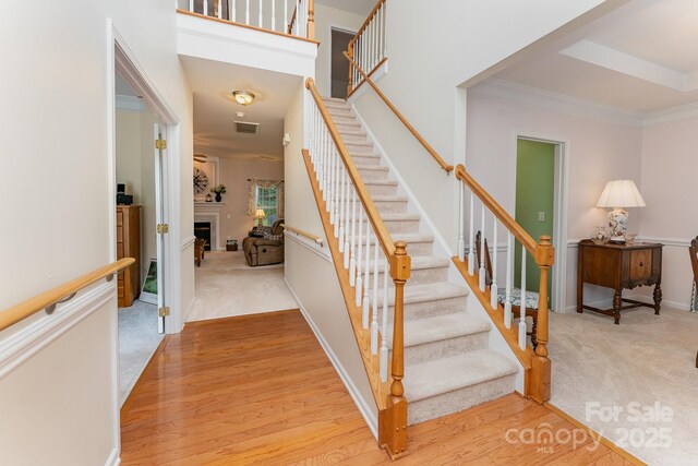 10322 Stoneykirk Ln, Charlotte, NC 28269 - stairway featuring carpet floors, wood finished floors, a fireplace, baseboards, and crown molding