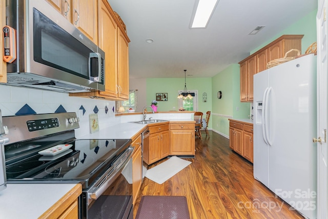10322 Stoneykirk Ln, Charlotte, NC 28269 - kitchen with appliances with stainless steel finishes, a sink, dark wood-type flooring, a peninsula, and light countertops