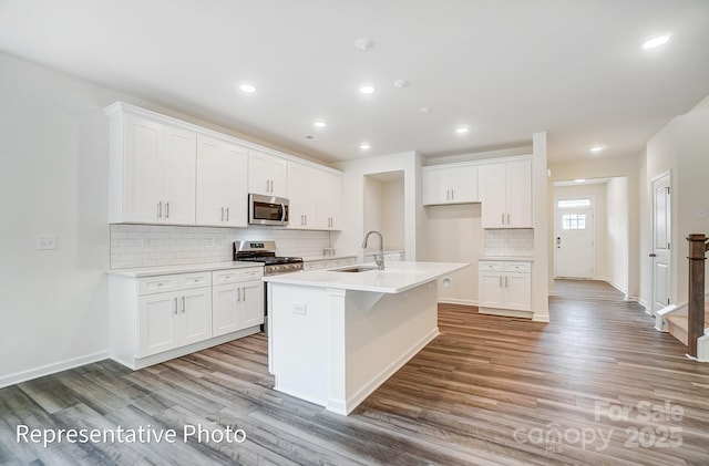 2233 Tabor Rd Unit 586, Sherrills Ford, NC 28673 - kitchen with appliances with stainless steel finishes, a sink, light wood-style floors, an island with sink, and tasteful backsplash