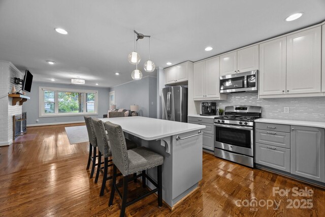 4106 Castlewood Rd, Charlotte, NC 28209 - kitchen featuring appliances with stainless steel finishes, gray cabinets, light countertops, tasteful backsplash, and open floor plan