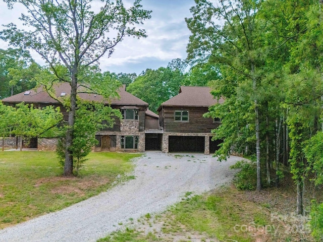 view of front of home with dirt driveway, an attached garage, stone siding, and a front yard