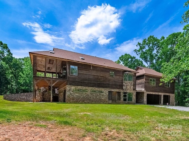 back of house with stone siding, a yard, and a deck