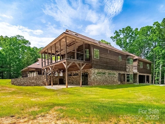 rear view of property featuring stone siding, a yard, and a patio area
