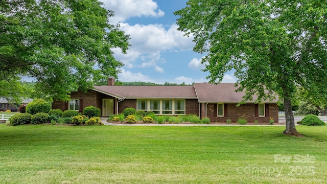 ranch-style home with a front yard, brick siding, and a chimney