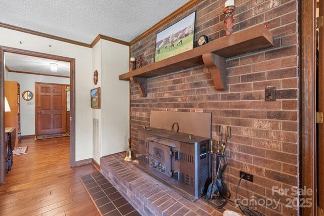 living area with wood-type flooring, a textured ceiling, ornamental molding, and baseboards