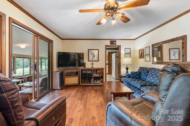 living room featuring hardwood / wood-style floors, ceiling fan, crown molding, and a textured ceiling