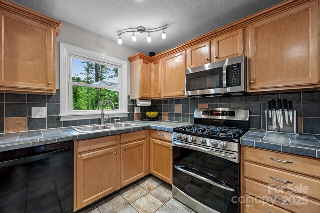 931 Indian Hill Rd, Hendersonville, NC 28791 - kitchen with stainless steel appliances, a sink, backsplash, tile countertops, and a textured ceiling
