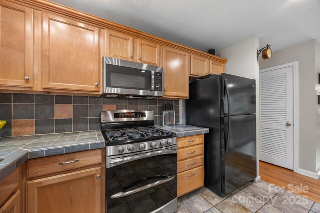 931 Indian Hill Rd, Hendersonville, NC 28791 - kitchen featuring appliances with stainless steel finishes, tile countertops, tasteful backsplash, and light tile patterned floors