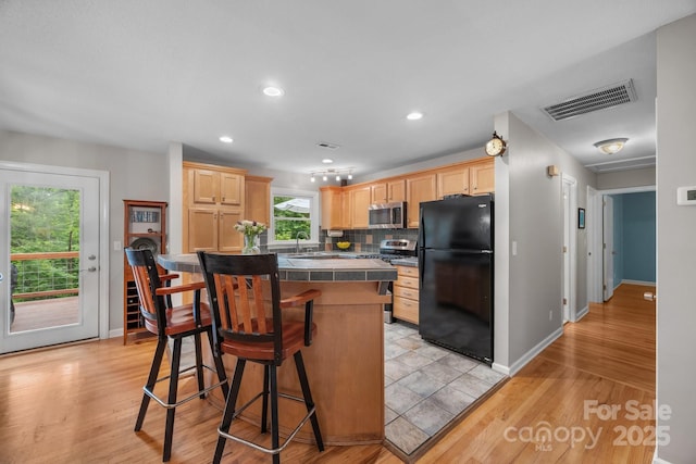 931 Indian Hill Rd, Hendersonville, NC 28791 - kitchen with appliances with stainless steel finishes, light brown cabinetry, tile counters, baseboards, and a breakfast bar area