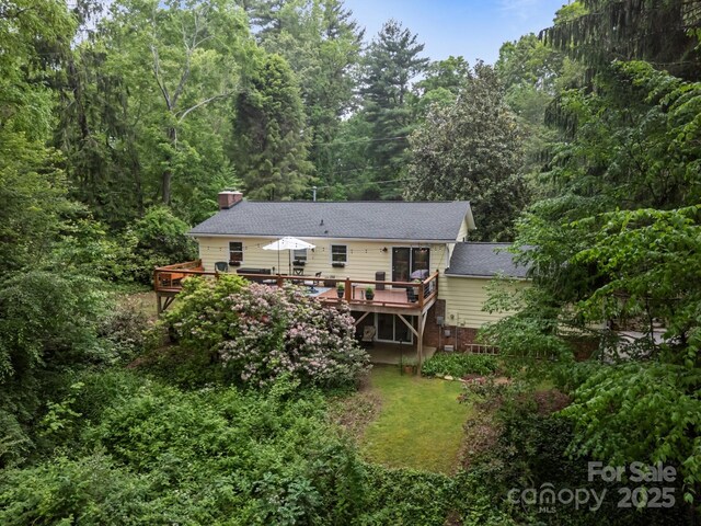 931 Indian Hill Rd, Hendersonville, NC 28791 - rear view of house featuring a deck, a chimney, a wooded view, and roof with shingles