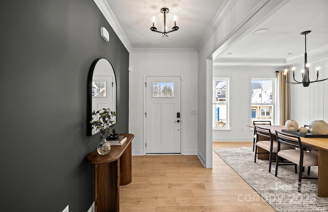 foyer entrance featuring a chandelier, light wood-type flooring, and ornamental molding