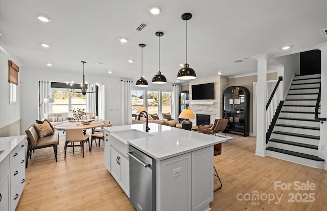 kitchen featuring a sink, open floor plan, dishwasher, a fireplace, and light wood finished floors