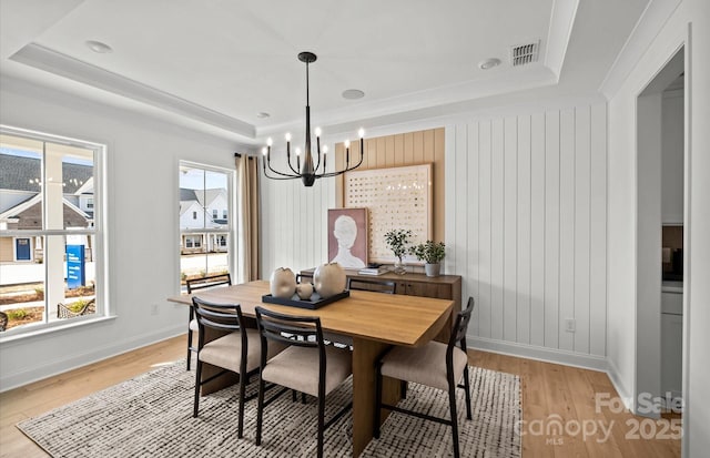 dining room featuring a raised ceiling, a chandelier, light wood-style flooring, and baseboards