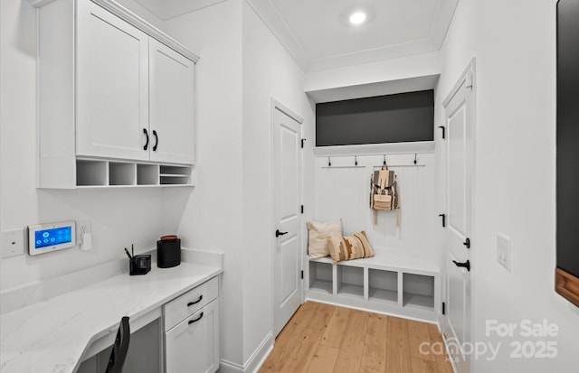 mudroom featuring light wood-style floors, ornamental molding, built in study area, and baseboards