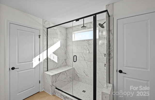 full bath with a marble finish shower and tile patterned flooring